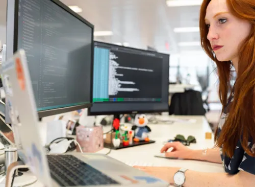 Desarrolladora trabajando con código en varios monitores