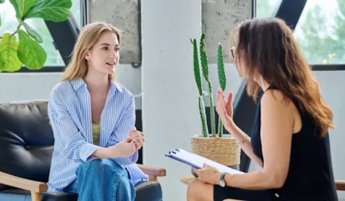 Dos mujeres conversan mientras una de ellas sostiene un portapapeles.