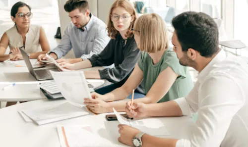 Equipo de profesionales reunido para analizar documentos y datos empresariales