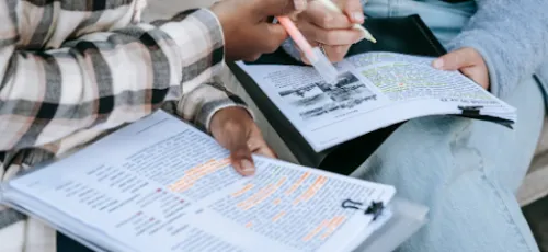 Estudiantes revisando y subrayando apuntes en grupo
