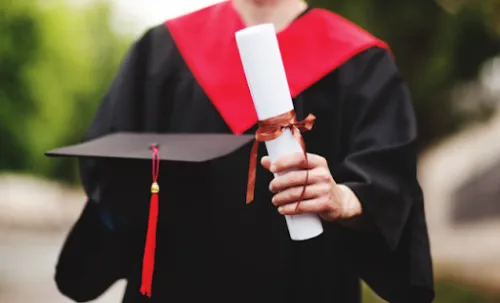 Persona graduada sosteniendo un título universitario y un birrete
