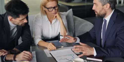 Tres profesionales reunidos analizando un informe con gráficos empresariales