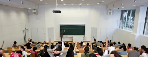 Personas con mano levantada en aula de clase